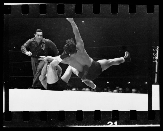Two men wrestling with a referee nearby