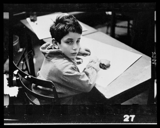 Young boy, half-length portrait, seated at desk, in classroom in Chicago, Illinois