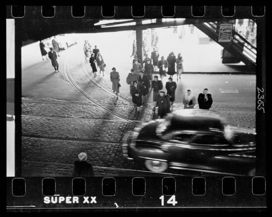 View from above of automobile and pedestrians on street below the "L" elevated railway in Chicago, Illinois